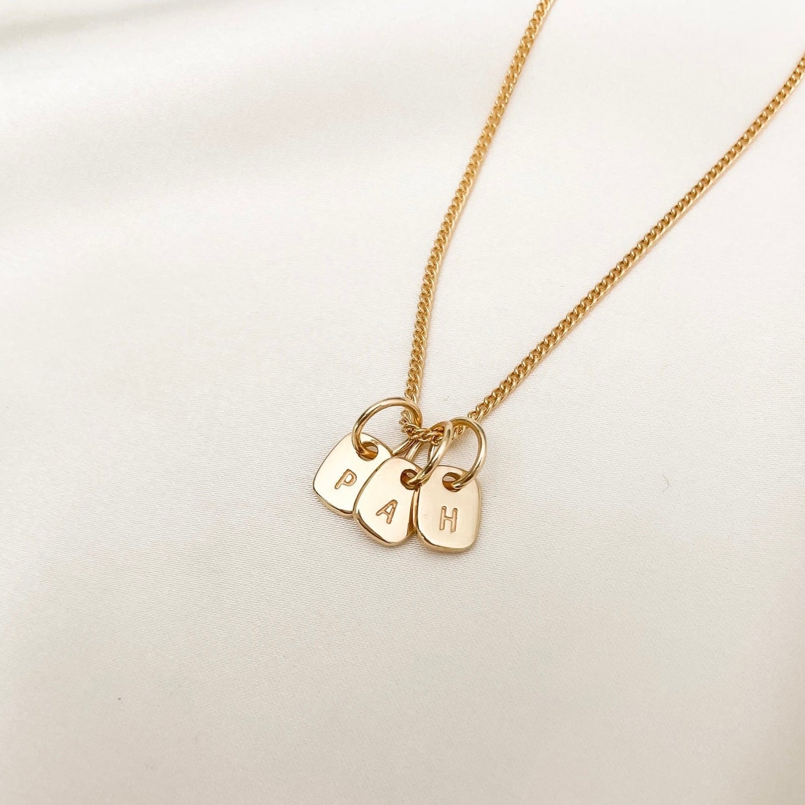 A Gold Fine Curb Necklace Chain with three Mini Rectangular Initial Pendants on it