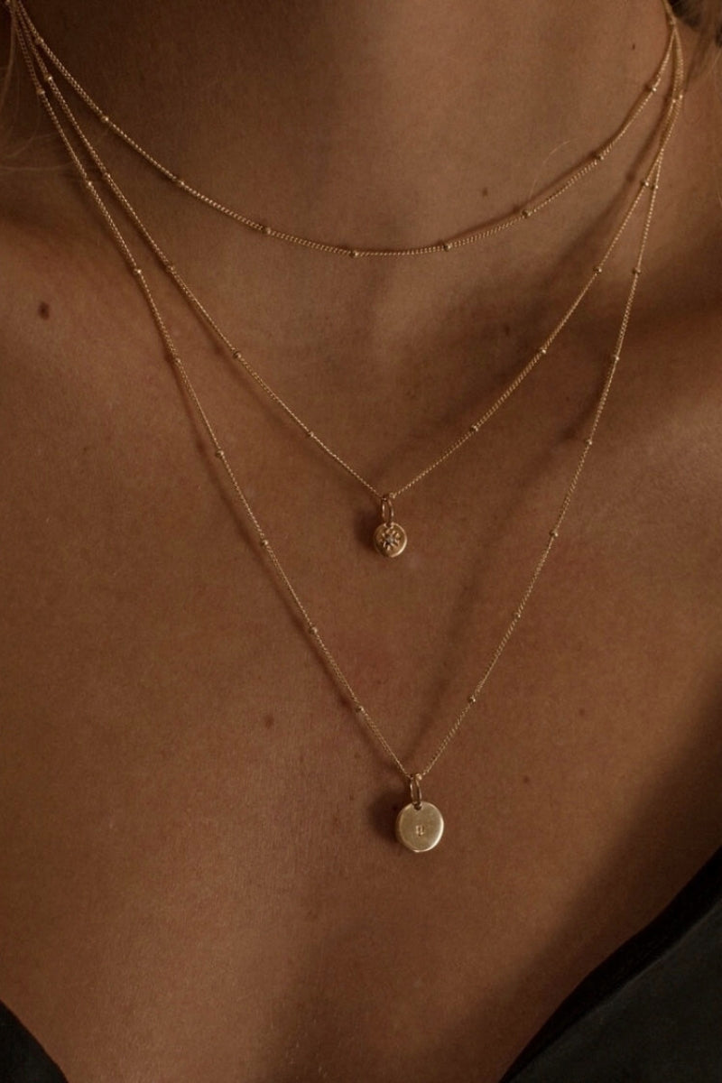 All three lengths of the gold ball chain necklace are shown close up in this layered necklace look. The 35cm length is worn as a choker style necklace, the 45cm length has a vintage pearl pendant and the 50cm length has the gold vermeil initial pendant (10mm)