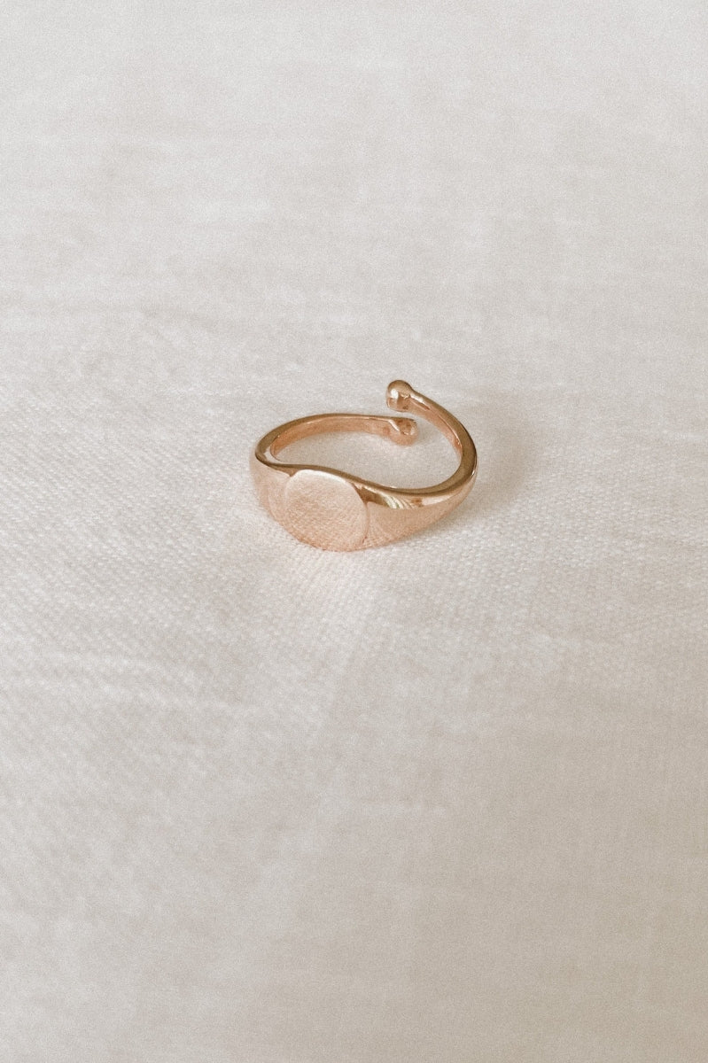 Solid 9ct Gold Signet ring sitting on white linen.  The image shgows the adjustable sides on the child sized ring.