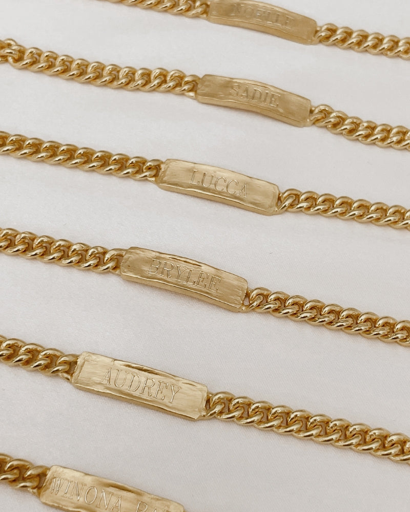 A row of Baby Sized Signature Barcelets all engraved with a name on the front of them by Bluebird Jewellery.