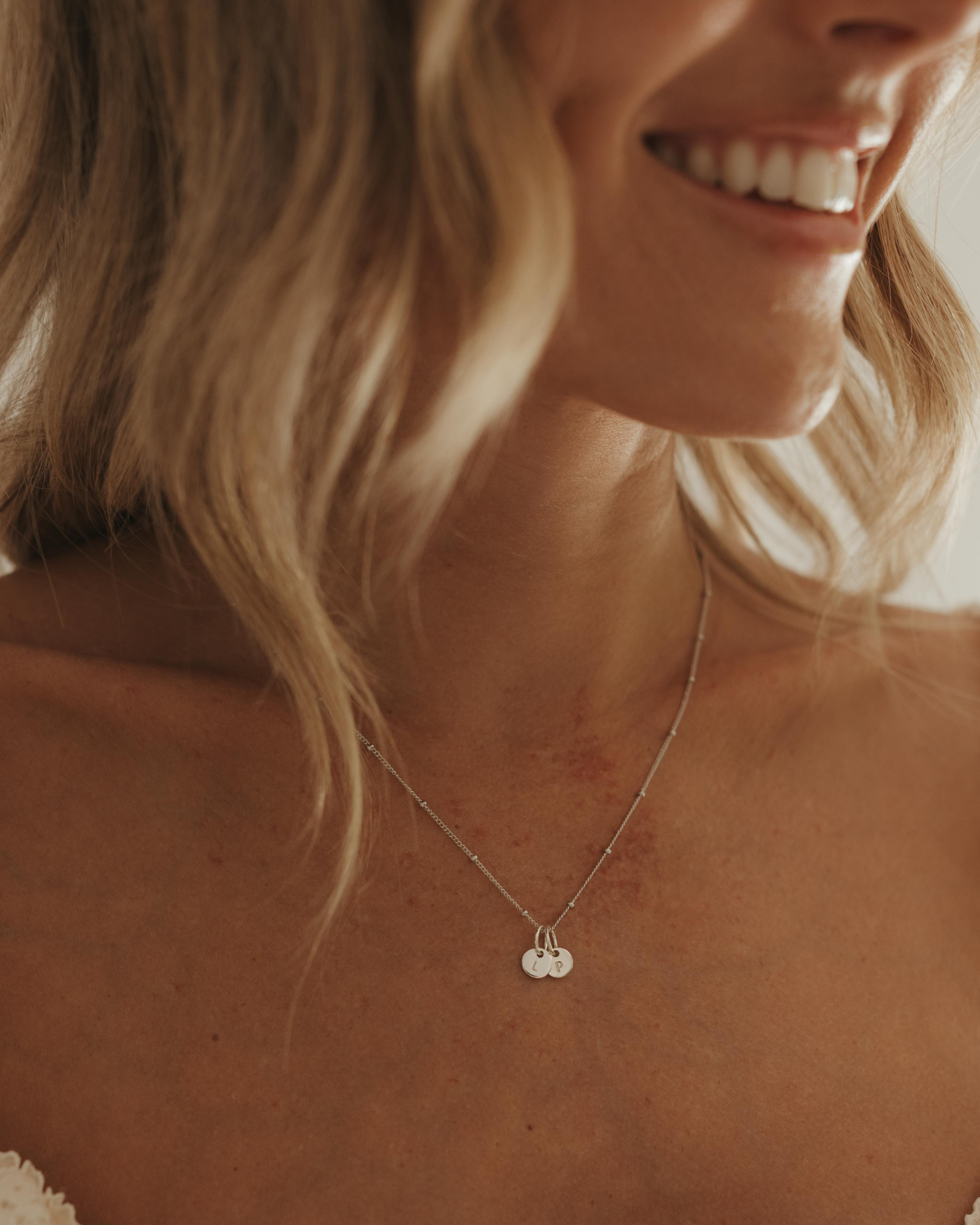 Woman wearing a delicate necklace with a initial pendants.
