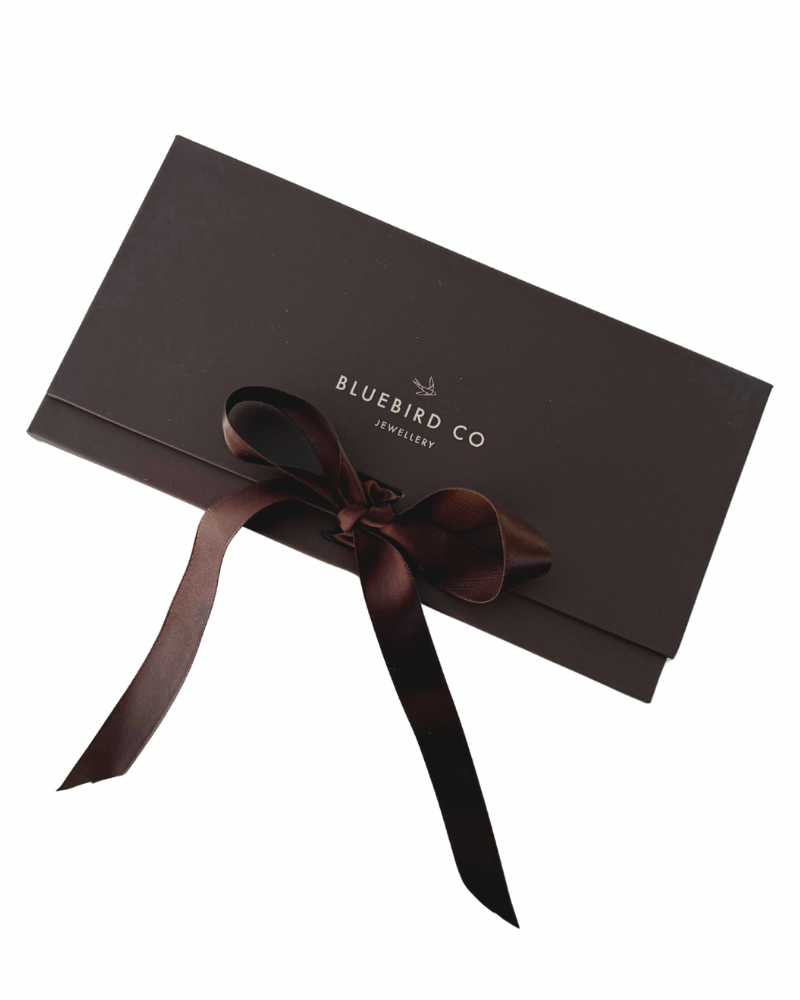 A detailed image of a Bluebird Co chocolate brown gift box with ribbon bow, an elegant presentation box for Bluebird Jewellery gifting.