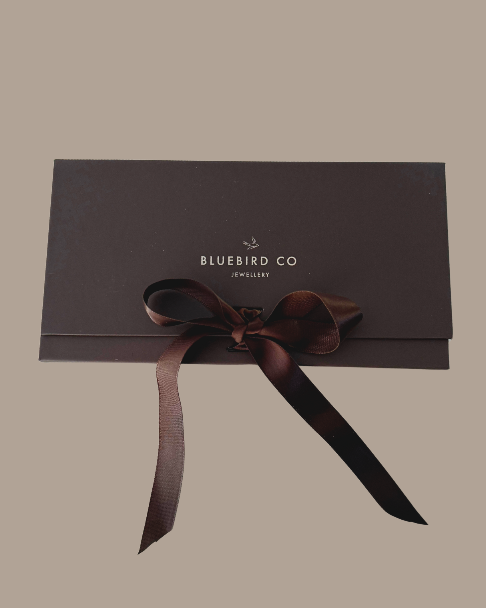 A detailed image of a Bluebird Co chocolate brown gift box with ribbon bow, an elegant presentation box for Bluebird Jewellery gifting.