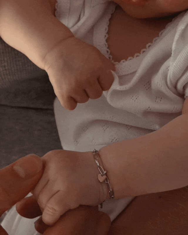 Bluebird Co's poise bracelet in silver on newborn baby hand.