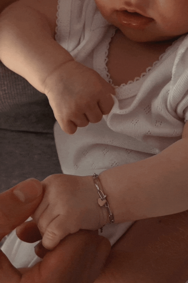 Bluebird Co's poise bracelet in silver on newborn baby hand.