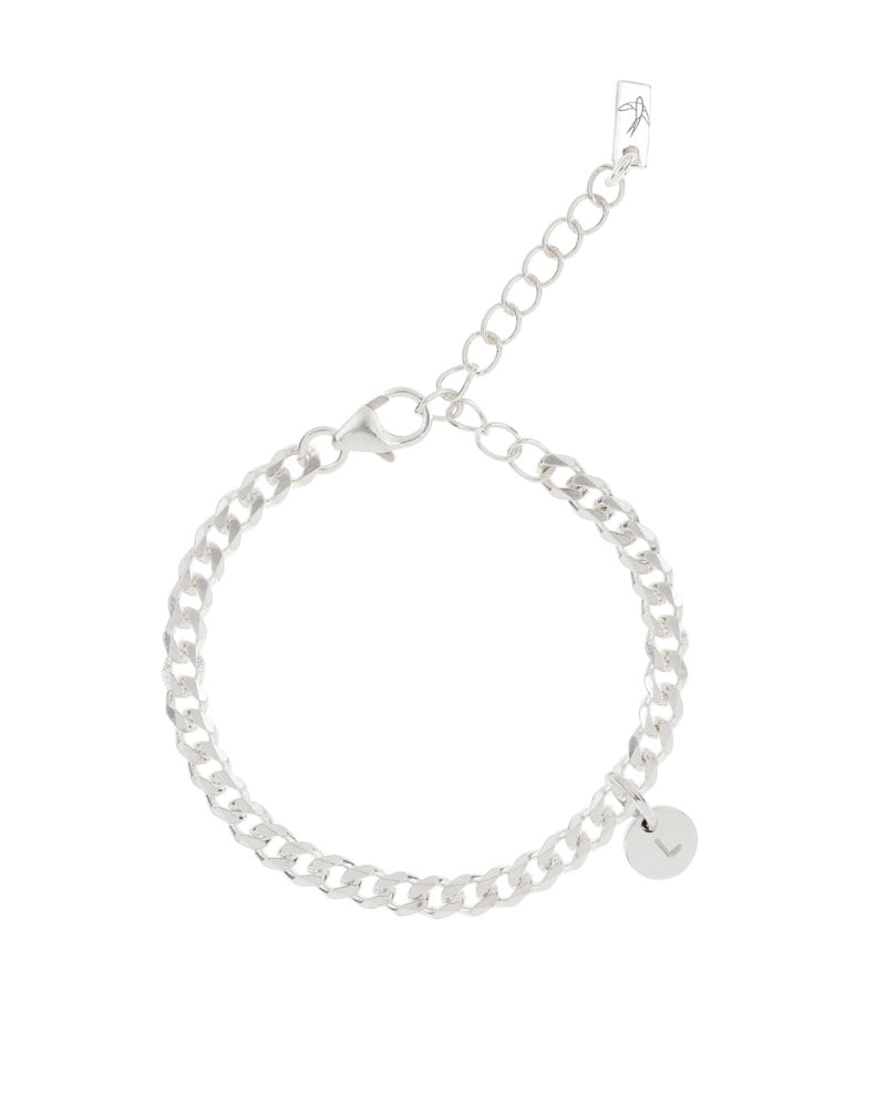 A minimalist silver anklet with a round engraved pendant, photographed on a white background to showcase its craftsmanship and simplicity.