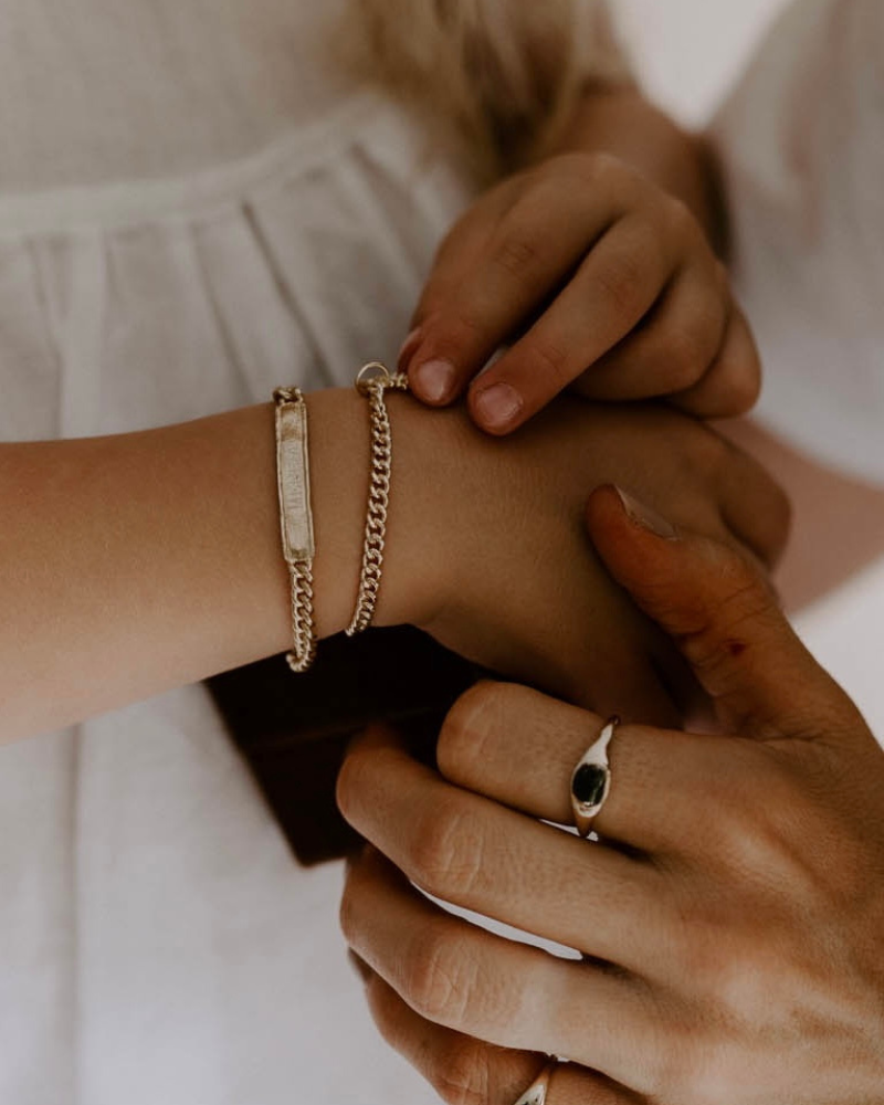 A woman and child wearing personalised gold bracelets and signet rings styled together for an elegant everyday look by Bluebird Jewellery