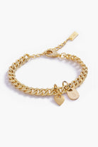 A close-up of a personalised gold bracelet with heart charm and solid gold initial pendant.