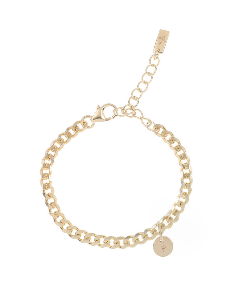 A close-up of a gold anklet with engraved initial pendant, designed as a simple and elegant everyday piece.
