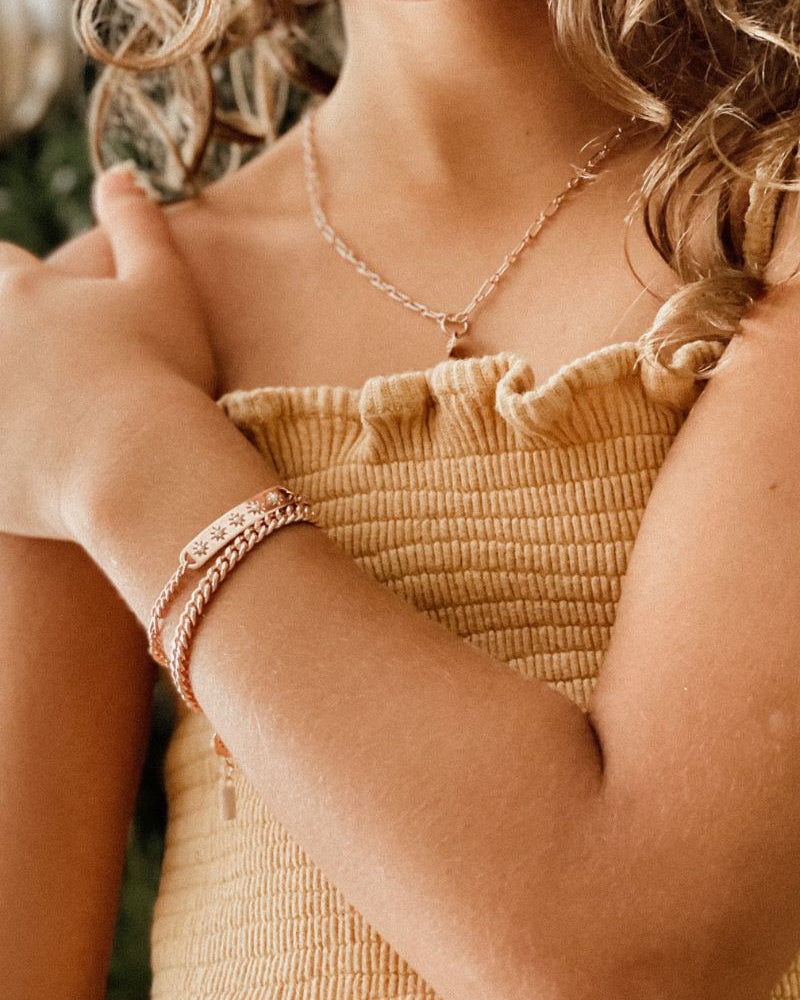 Two matching rose gold bracelets worn by a child, crafted in a delicate fine chain design by Bluebird Jewellery