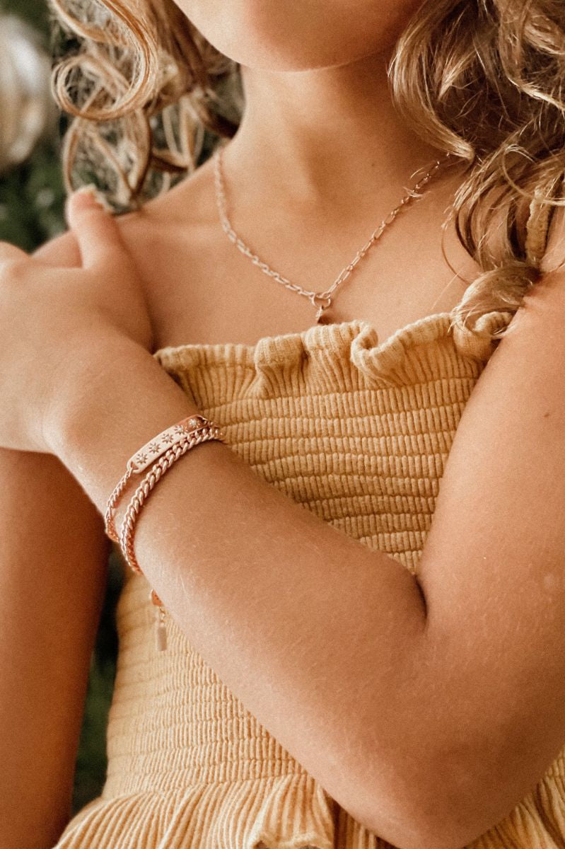 Two matching rose gold bracelets worn by a child, crafted in a delicate fine chain design by Bluebird Jewellery