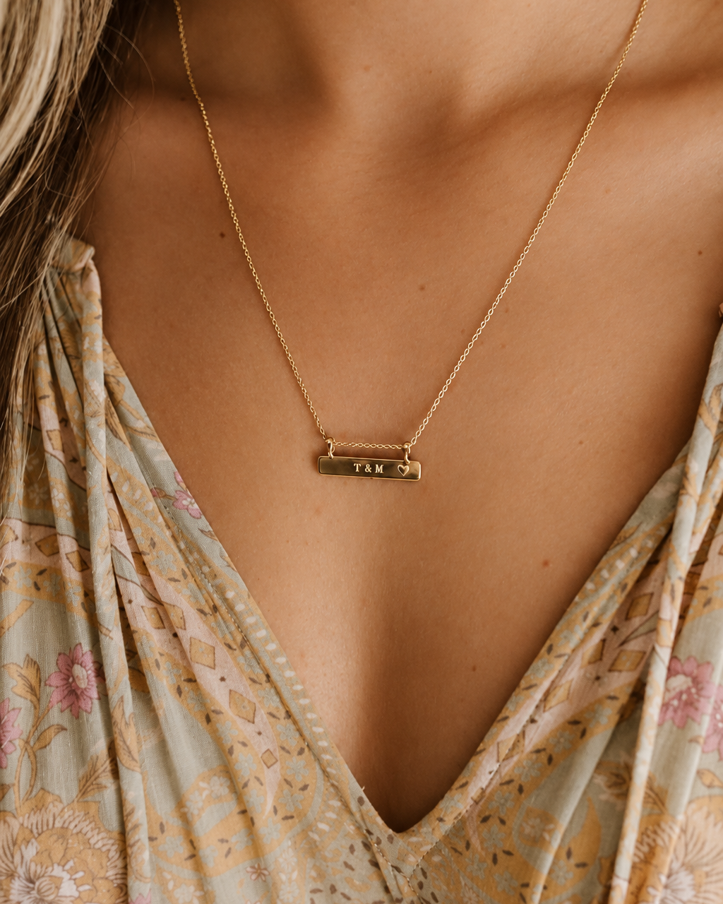 a 50+5cm Darling Bar necklace with initials engraved on it rests elegantly on a woman's neckline