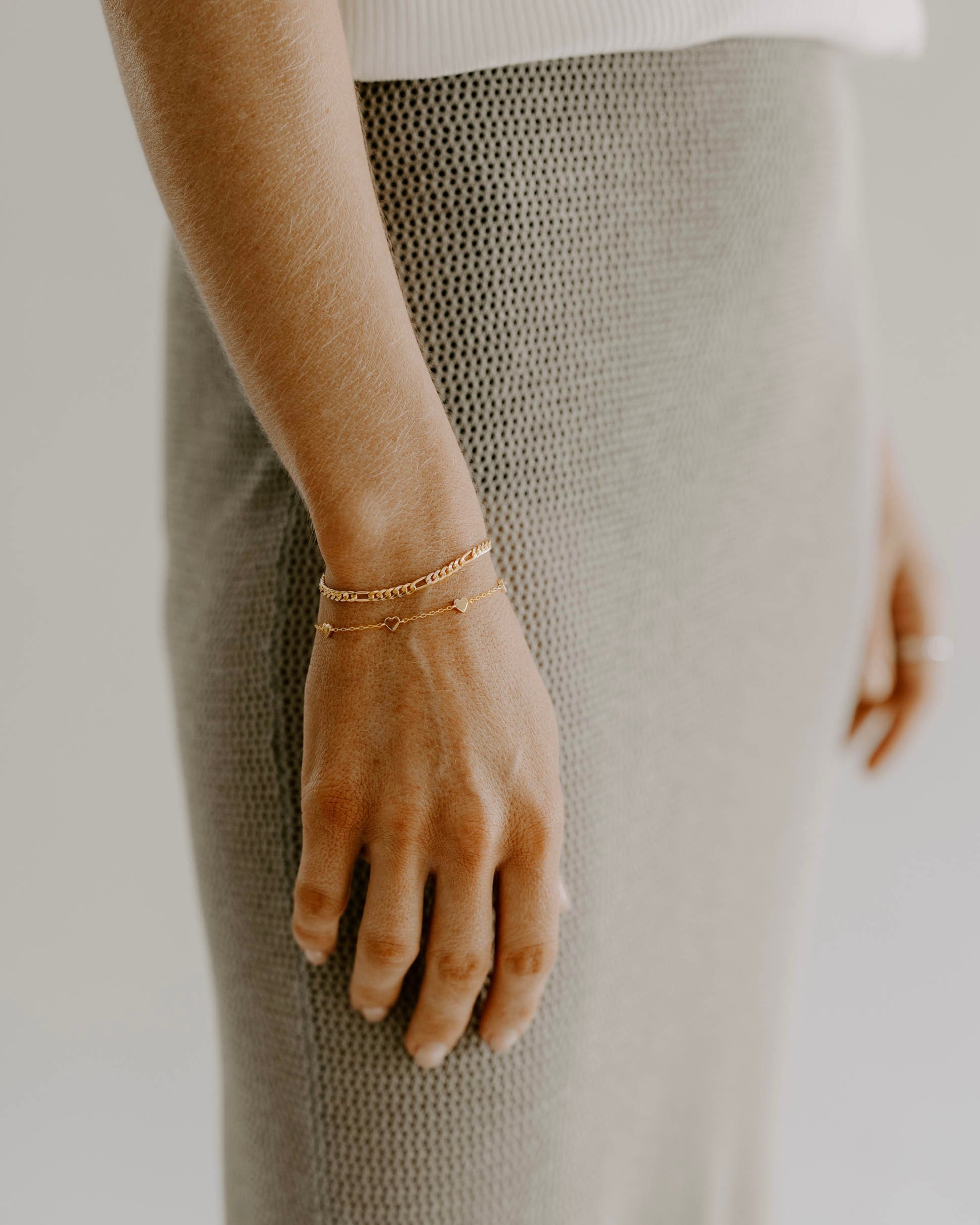 A woman wearing a Darling Heart Bracelet by Bluebird Jewellery, crafted with five petite hearts for a sweet and timeless look, perfect alongside your Bluebird Co collection.