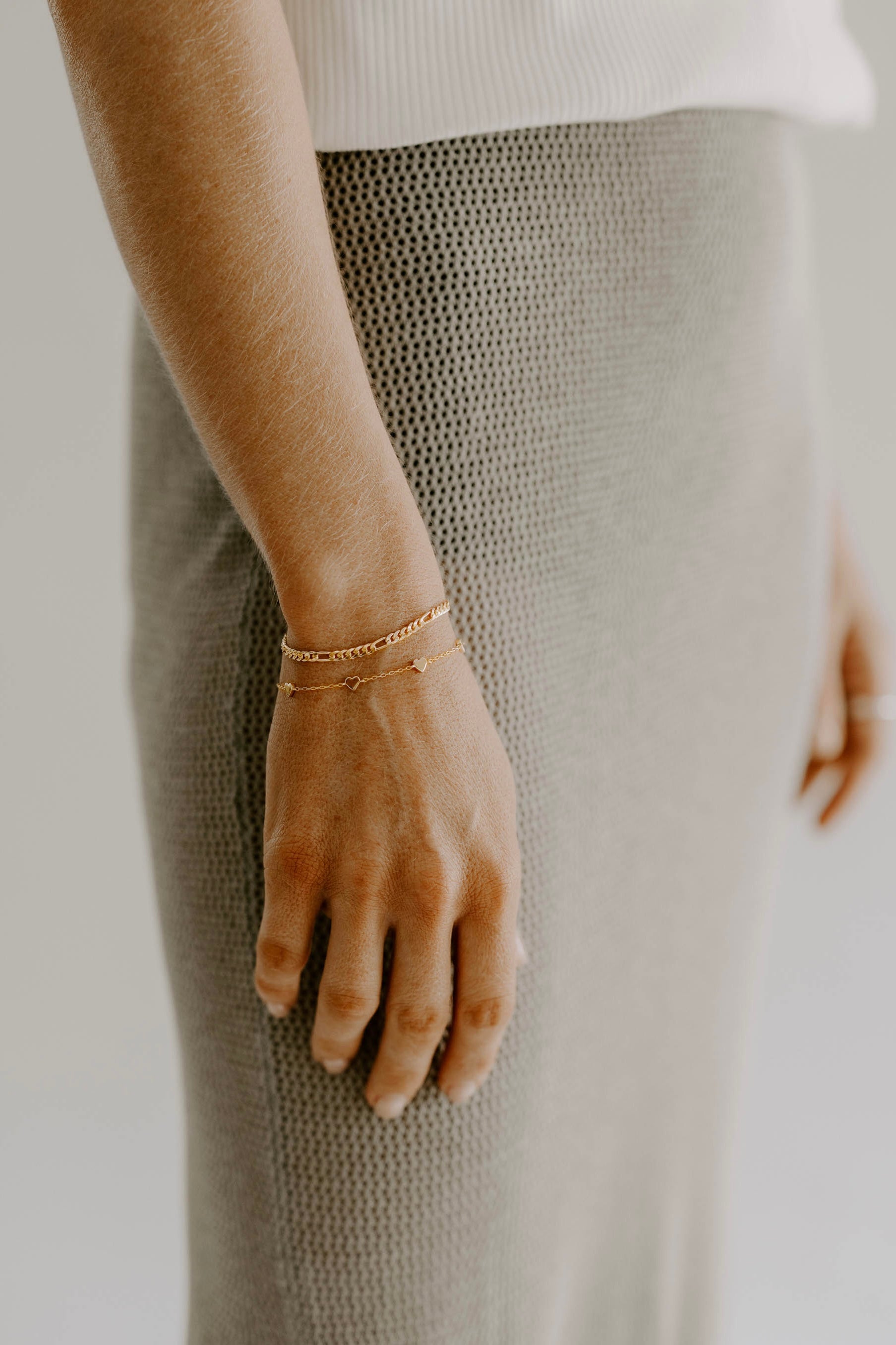 A woman wearing a Darling Heart Bracelet by Bluebird Jewellery, crafted with five petite hearts for a sweet and timeless look, perfect alongside your Bluebird Co collection.