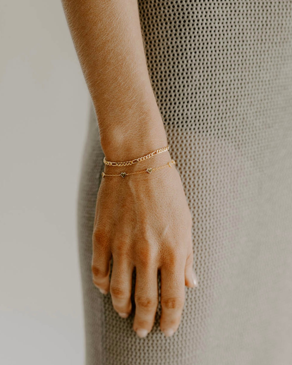 A rose gold figaro bracelet and Rose Gold Heart Bracelet are worn together by Bluebird Jewellery