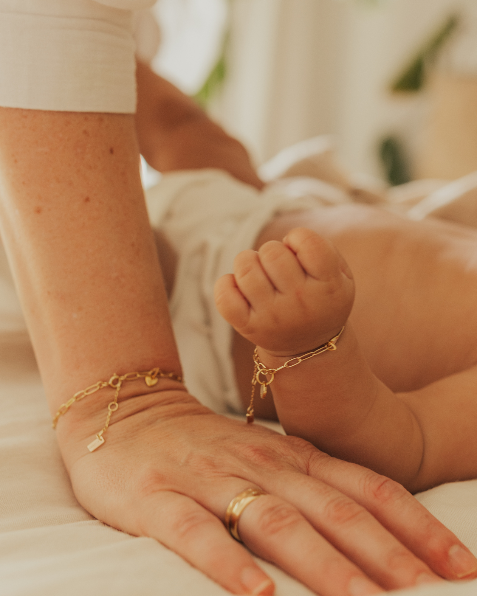 A detailed photo showing matching Posie Bracelets on a mother and baby’s wrists, crafted as sentimental personalised jewellery pieces by Bluebird Jewellery.