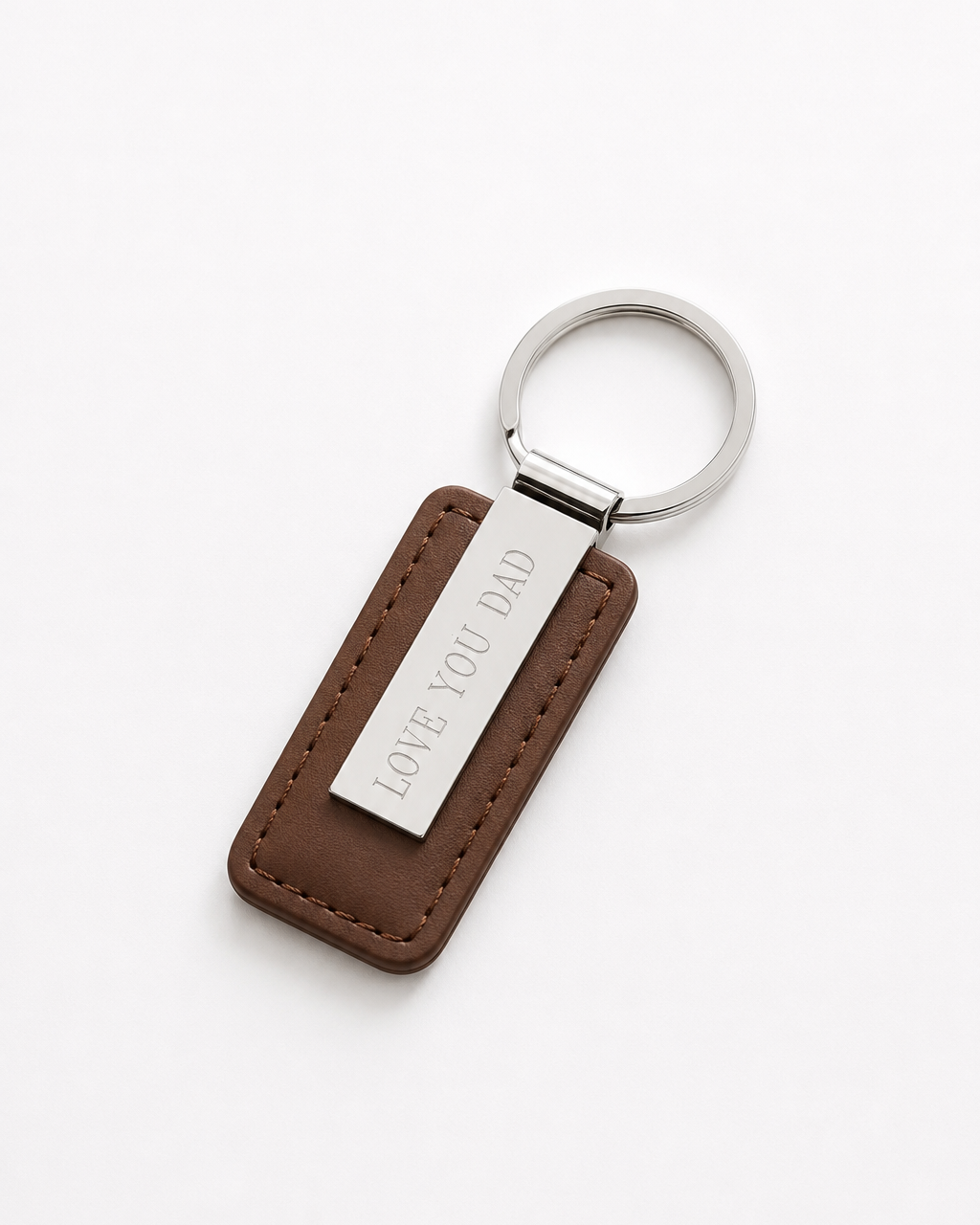 A brown leather keychain with a silver metal ring and a silver metal tag engraved with 'LOVE YOU DAD', shown on a clean white background.
