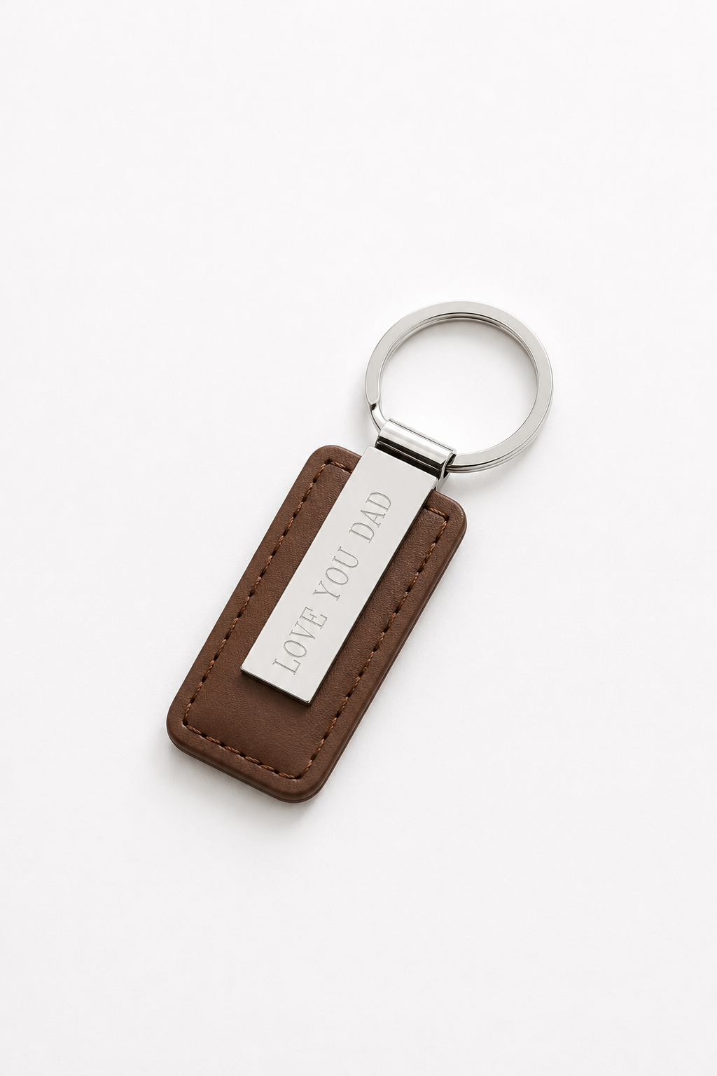 A brown leather keychain with a silver metal ring and a silver metal tag engraved with 'LOVE YOU DAD', shown on a clean white background.
