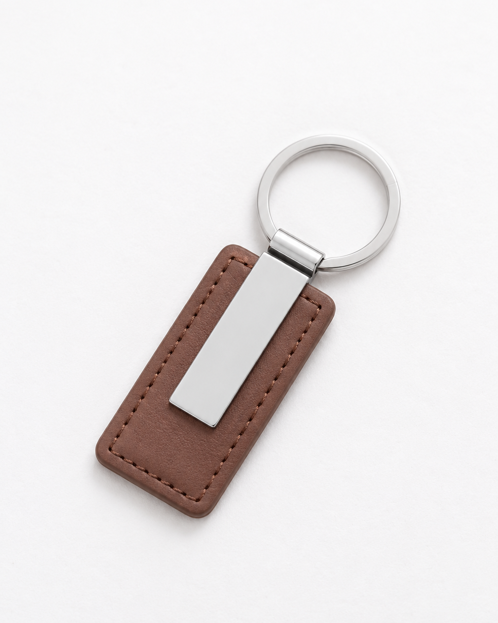 A brown leather keychain tag with a silver metal plate and a silver key ring, shown on a clean white background.