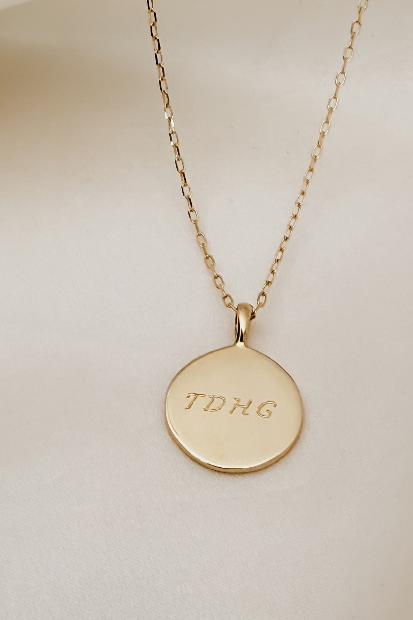 A beautiful close up image of a Soleil Pendant with 4 letters engraved on the front of it