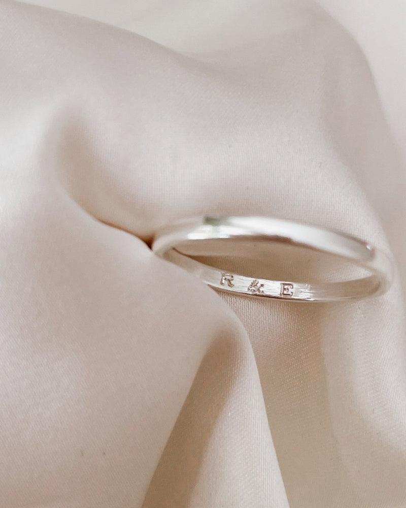 the inside of a pinky ring with the engraving of initials is shown.