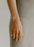 A rose gold figaro bracelet and Rose Gold Heart Bracelet are worn together.