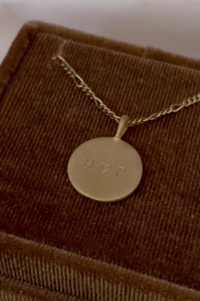 A Gold Signature Necklace with personalised engraving on it sitting inside a Bluebird Co velvet box