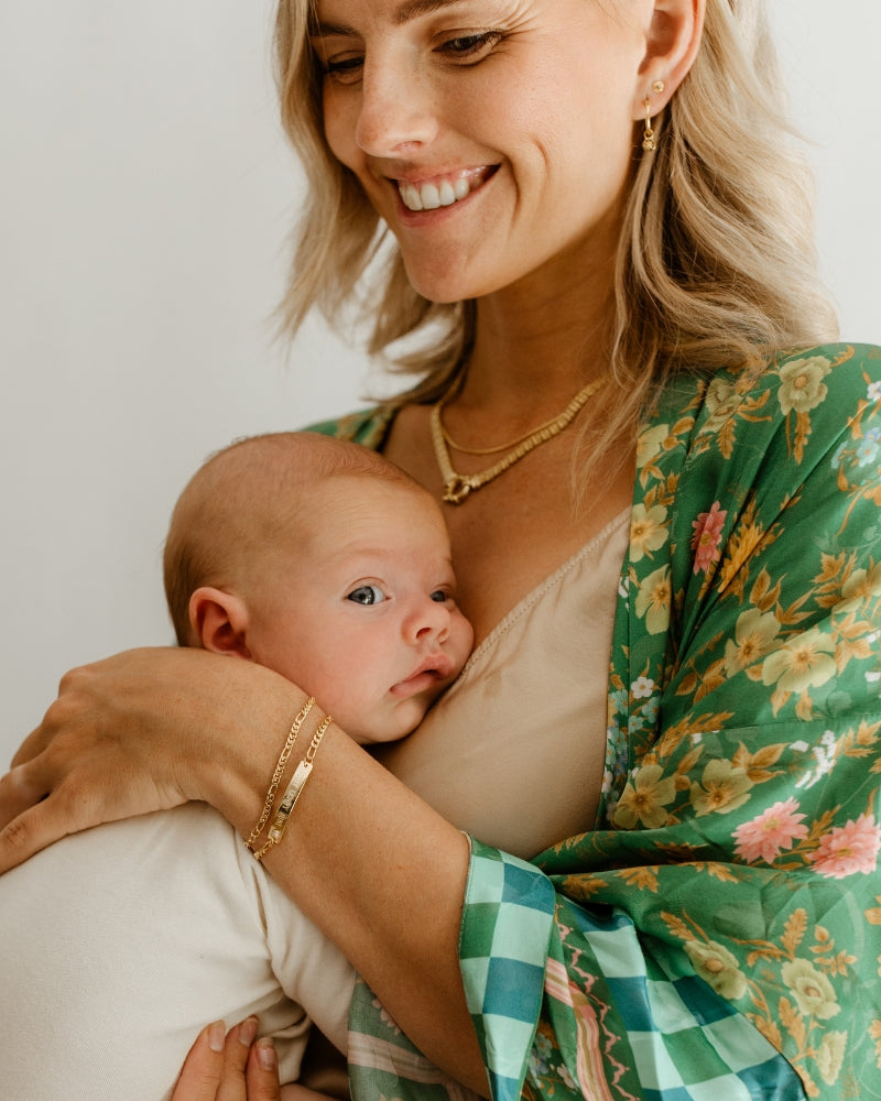 Mum and baby wear matching engraved gold jewellery—personalised bracelet designed for babies, kids, and adults by Bluebird Jewellery.