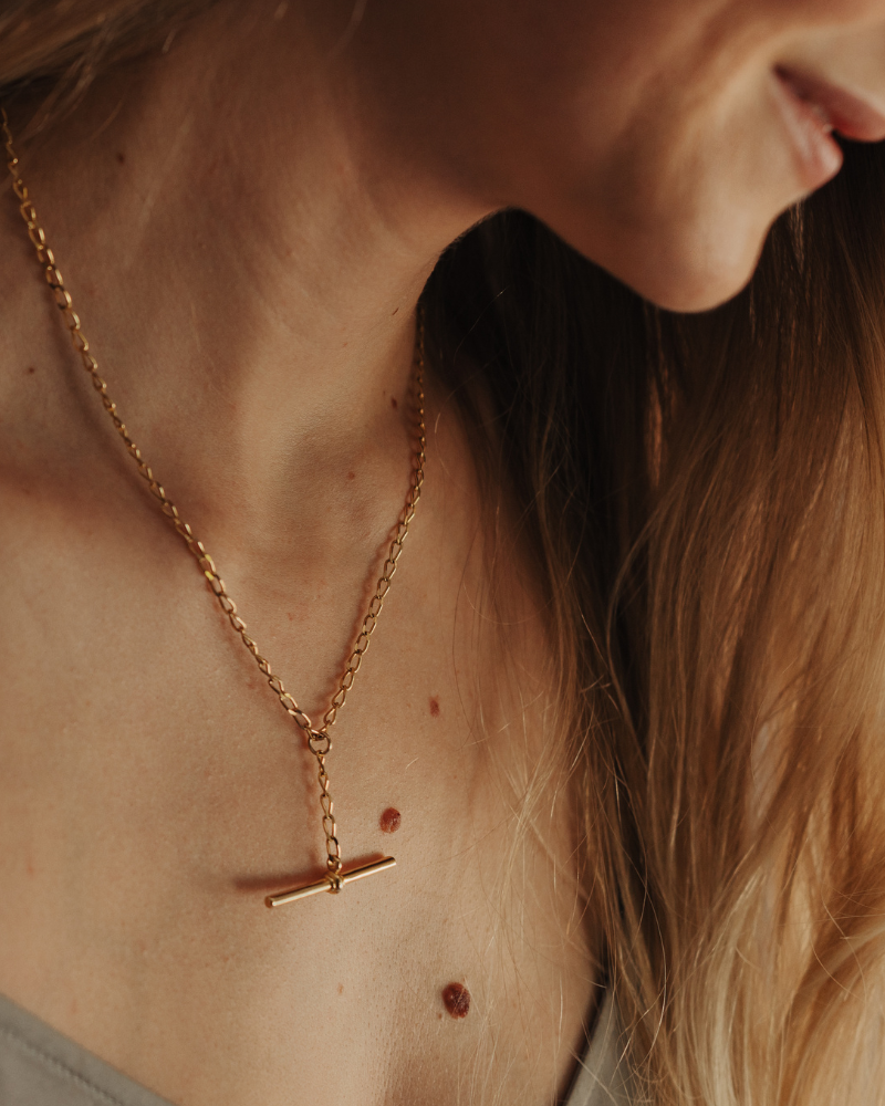 Close-up of a person wearing a gold necklace with a pendant.