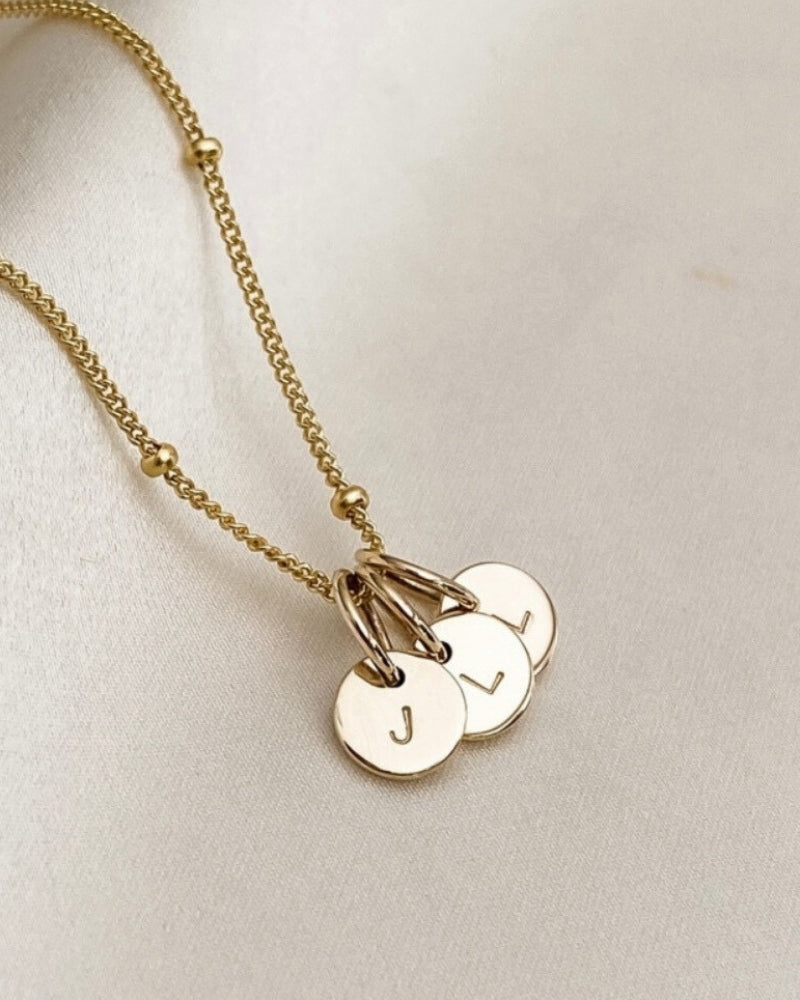 A close up of the solid 9ct gold initial pendants on a gold plated ball chain necklace