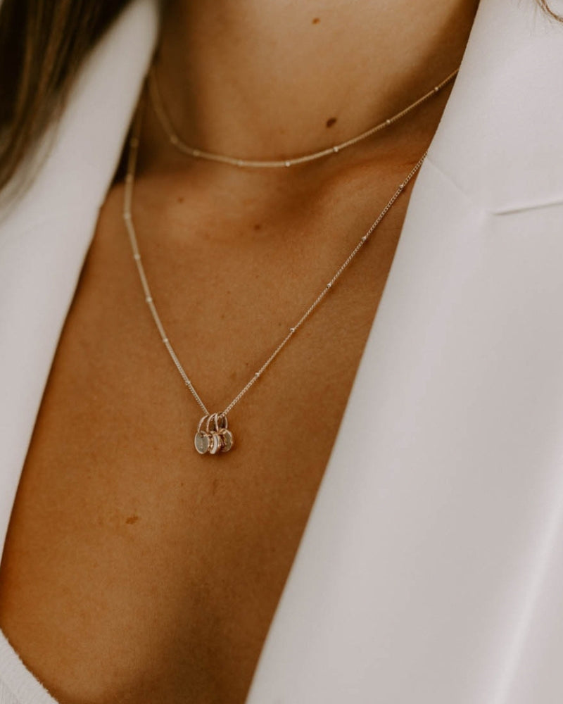 A side angle of three solid 9ct gold letter pendants on a gold ball chain necklace (45cm)