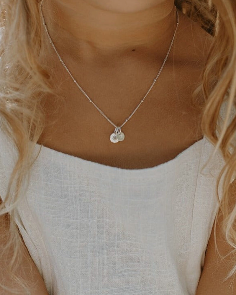A close up look at the Vintage Pearl necklace with Petite initial pendant in sterling silver that a young girl is wearing. She wears the 35cm length necklace.