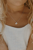 A close up look at the Vintage Pearl necklace with Petite initial pendant in sterling silver that a young girl is wearing. She wears the 35cm length necklace.