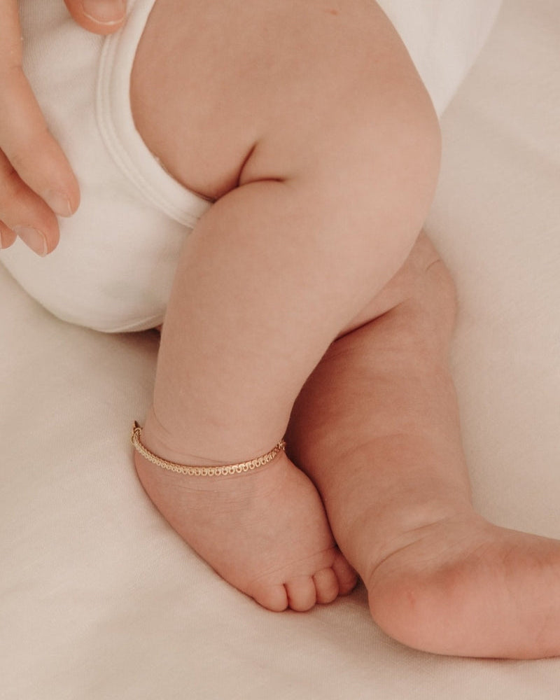 A detailed image of a baby’s ankle featuring a gold Lace Chain Anklet, designed as a delicate and meaningful jewellery keepsake.