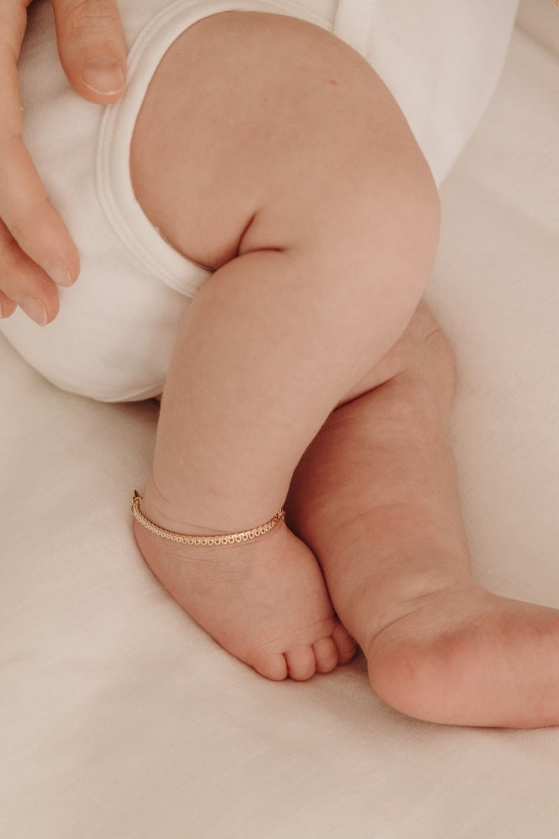 A detailed image of a baby’s ankle featuring a gold Lace Chain Anklet, designed as a delicate and meaningful jewellery keepsake.