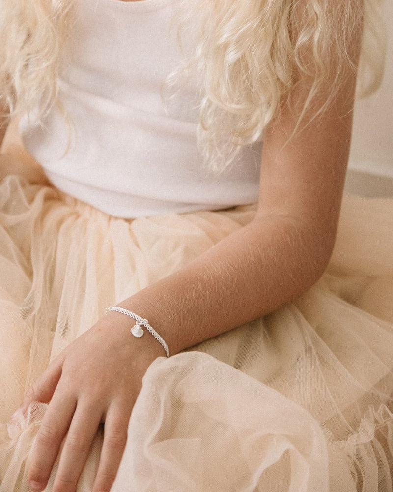 A child wearing a Lace Chain Anklet with a mermaid shell charm, designed as an elegant and whimsical piece of jewellery.