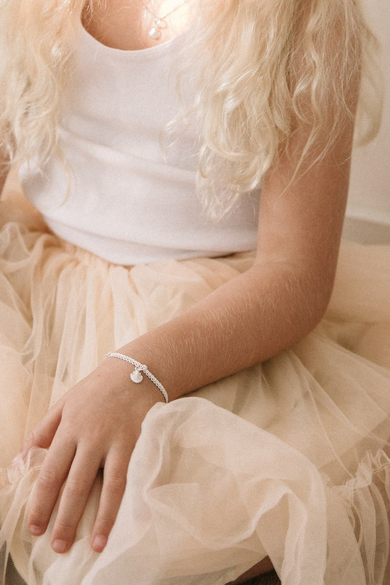 A child wearing a Lace Chain Anklet with a mermaid shell charm, designed as an elegant and whimsical piece of jewellery.