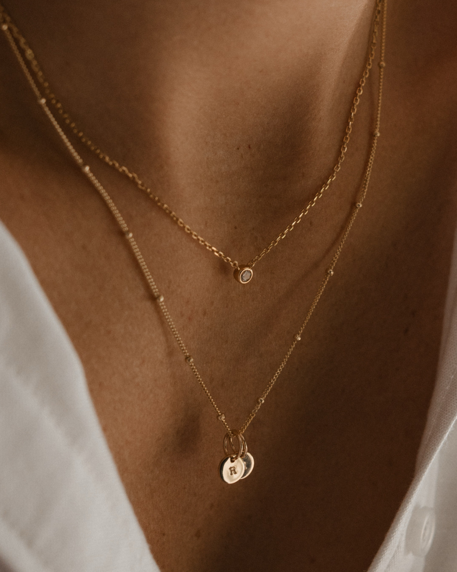 A woman wearing delicate Lumé Necklace and personalised necklace with engraves pendants by Bluebird Jewellery, designed as a radiant keepsake symbolising light, love, and personal strength.
