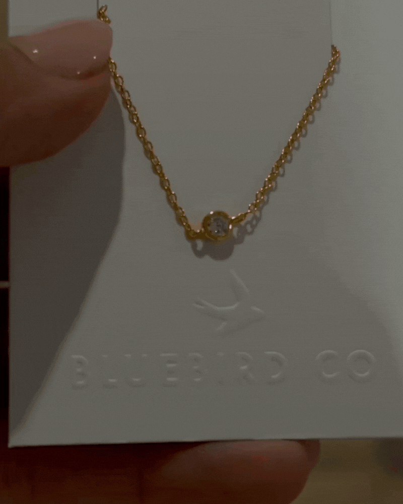 a close up of a gold bracelet with a cubic zirconia set within the chain.