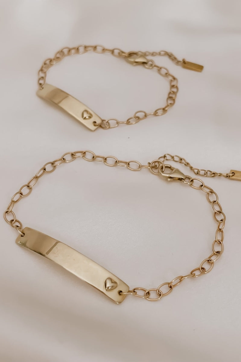 Matching solid gold Darling Bracelets for mum and baby shown flat lay with heart detail and chain link finish