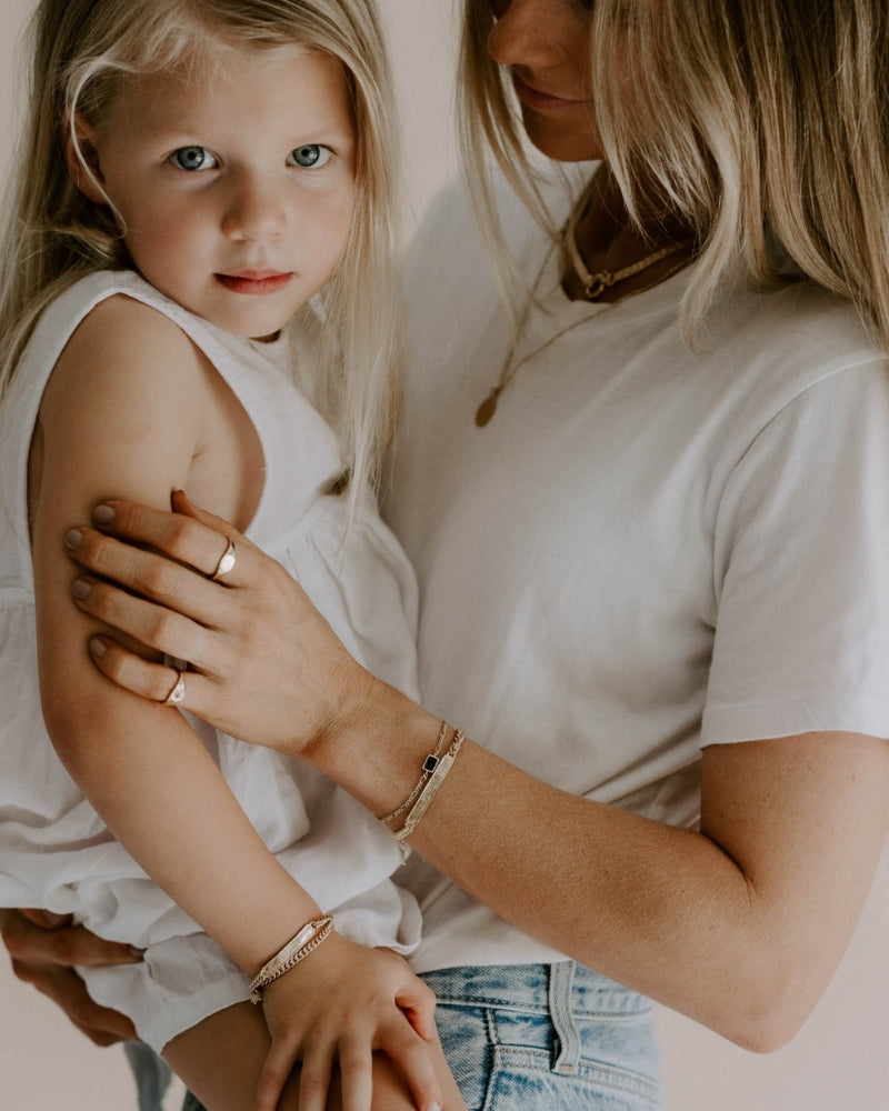 A mother and daughter are wearing matching Bluebird Co Signature Bracelets in Gold Vermeil with personalised engraving.