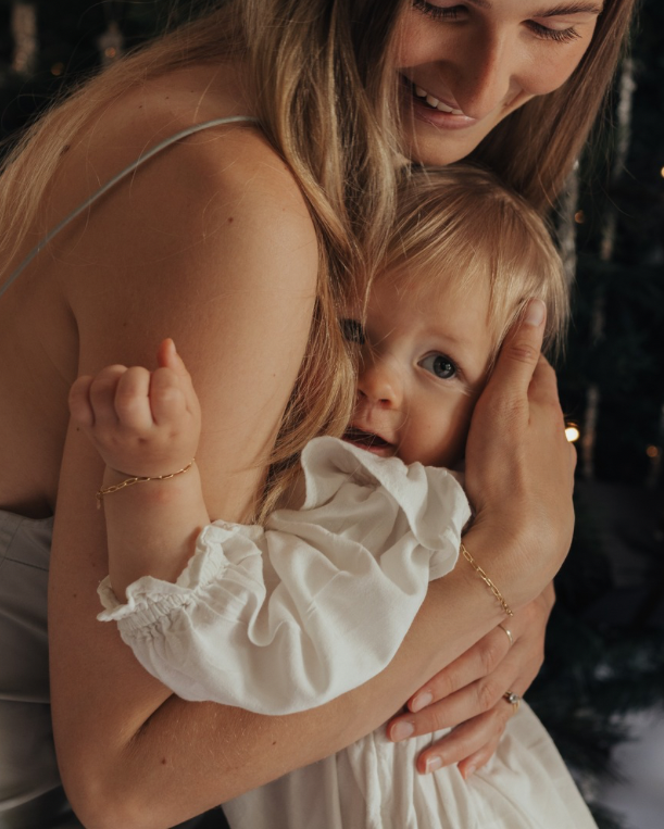 Woman holding a baby in front of a decorated Christmas tree