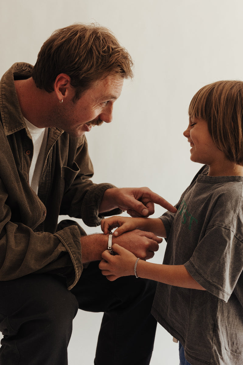Son gifting his father a Men's ID Bracelet and smiling and laughing together.