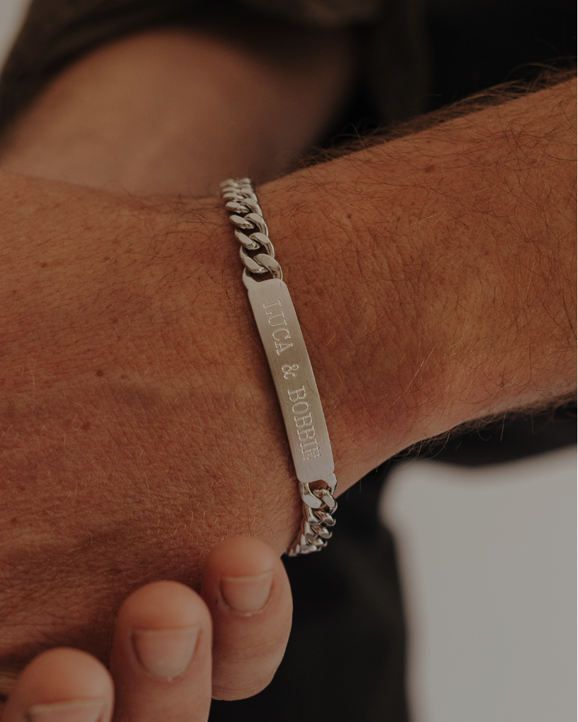 A man wearing an engraved ID bracelet with his children's names on it.