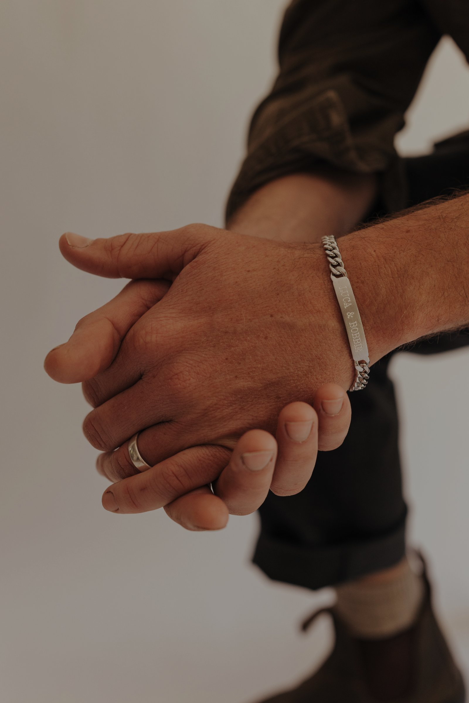 A man wearing an engraved ID bracelet with his children's names on it.
