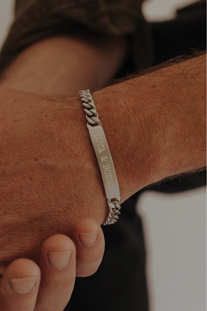 A man wearing an engraved ID bracelet with his children's names on it.