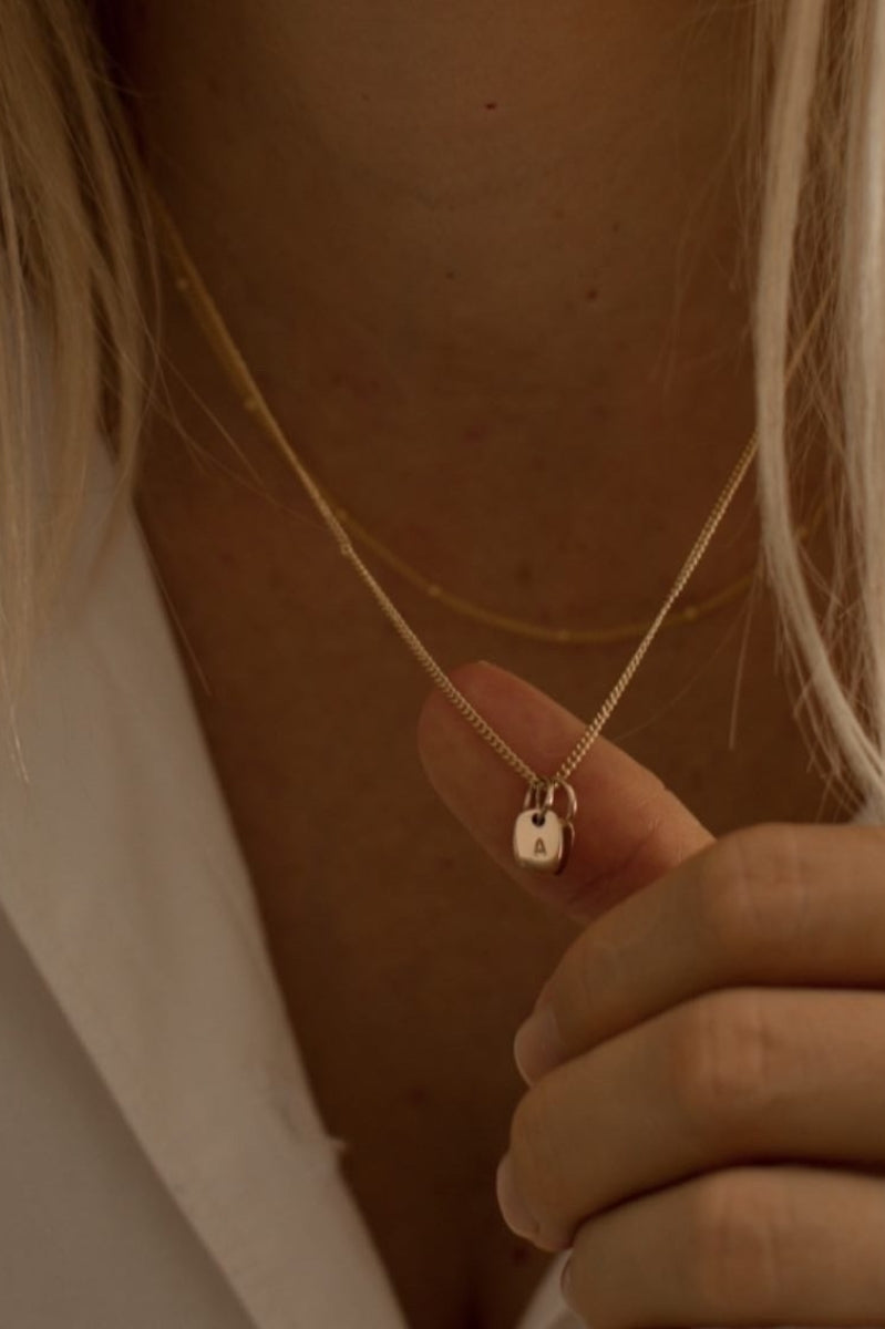 A fine curb chain necklace with the Mini Rectangular Pendants Bluebird Jewellery features gentle curves and a luxe, modern silhouette. Personalised with your chosen letter, it embodies feminine elegance and can be worn beautifully on any necklace, bracelet, or anklet chain.