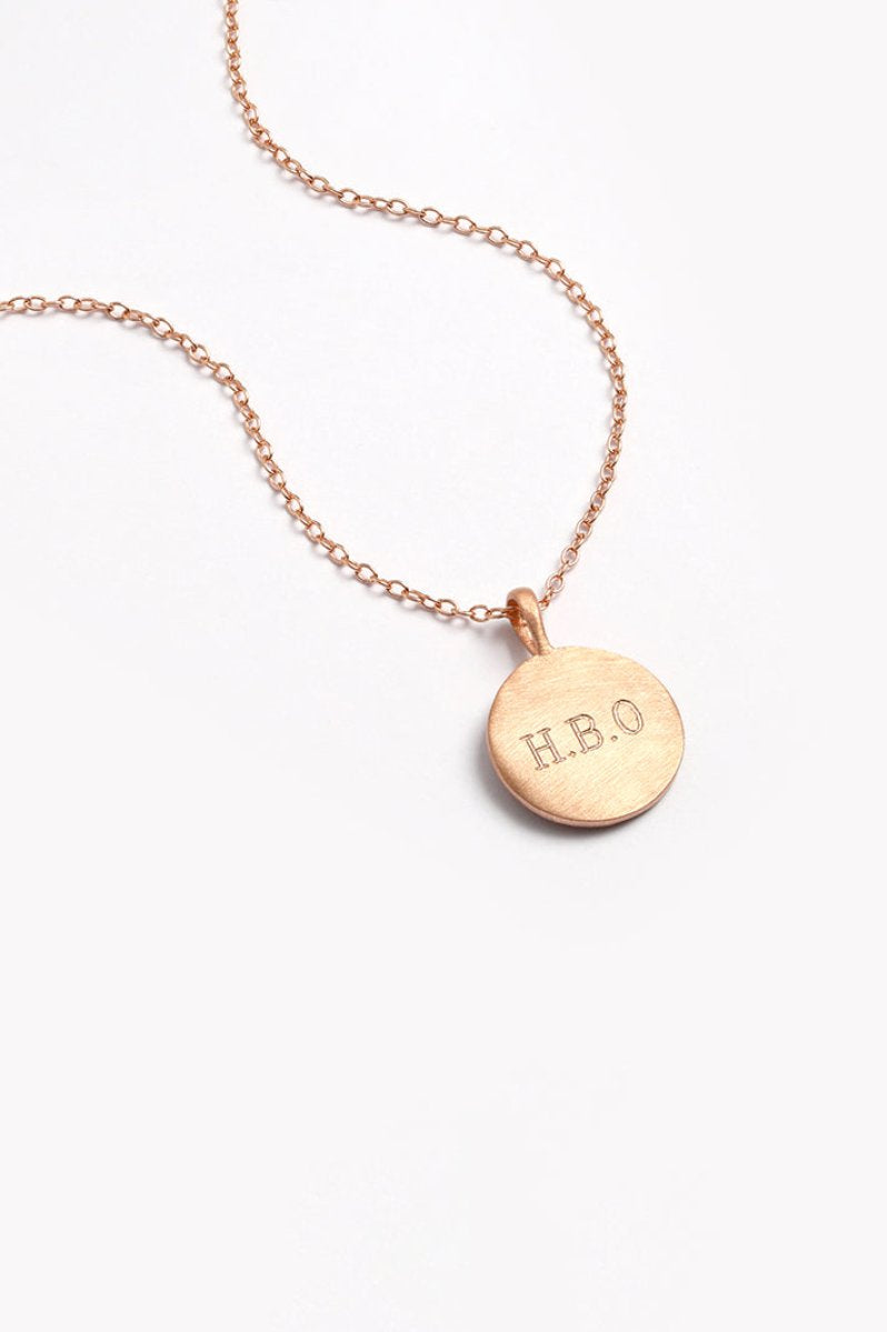 Close-up of Petite Signature Necklace in rose gold with engraved initials on a round pendant and fine chain for everyday wear.