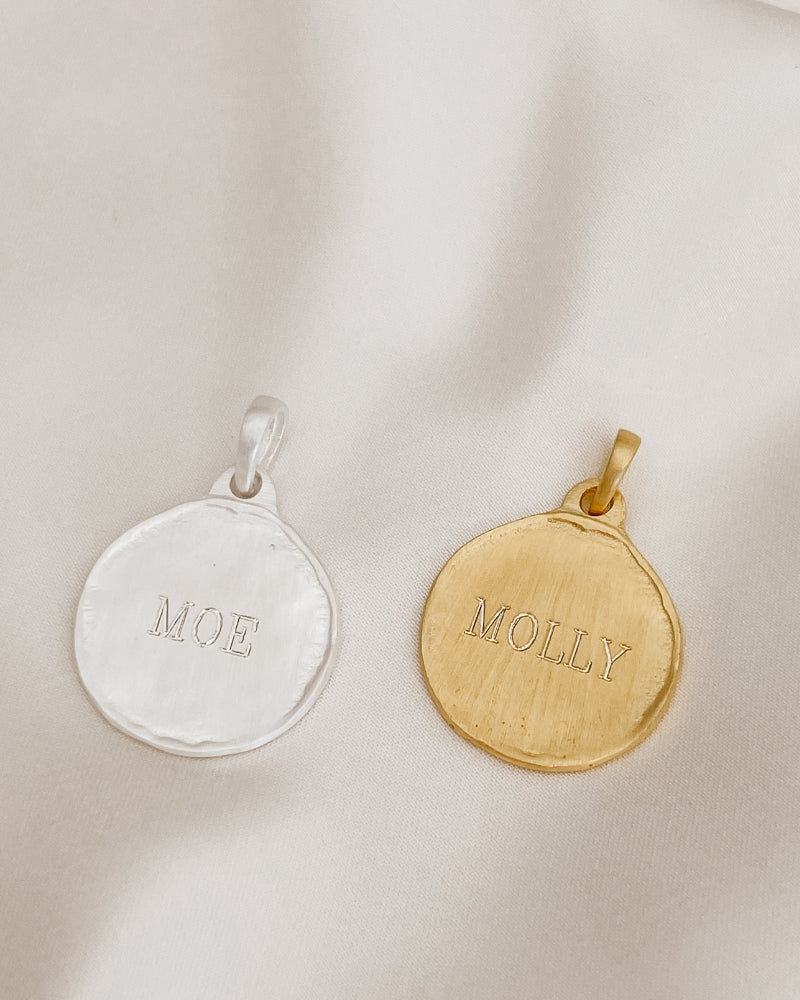 A silver and gold Petite Pet Pendnat sit alongside one another with personalised engraving on each.