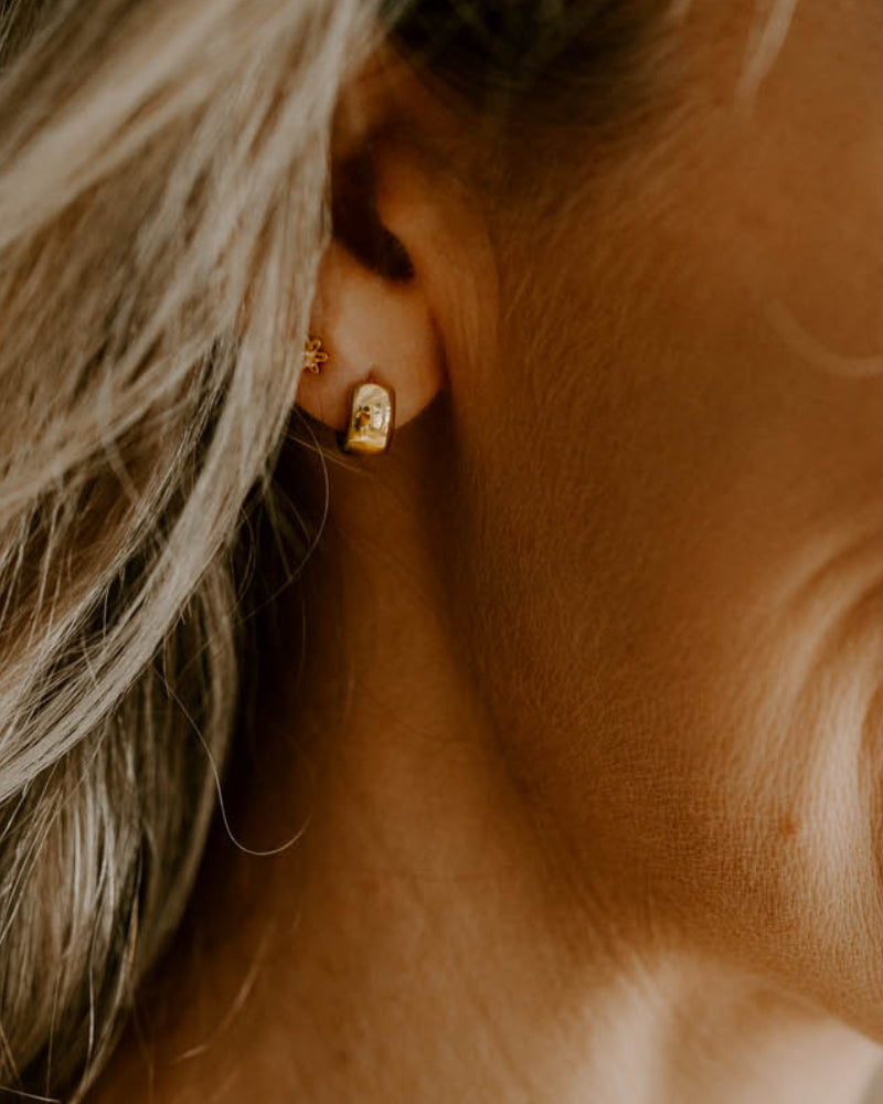 Petite Huggie earrings worn with Petite Daisy studs both in gold plated sterling silver.